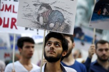 A man holds a poster with a drawing depicting a drowned Syrian toddler during a demonstration for refugee rights in Istanbul, Turkey, September 3, 2015. The distraught father of two Syrian toddlers who drowned with their mother and several other migrants as they tried to reach Greece identified their bodies on Thursday and prepared to take them back to their home town of Kobani. Abdullah Kurdi collapsed in tears after emerging from a morgue in the city of Mugla near Bodrum, where the body of his three-year old son Aylan washed up on Wednesday. The image of Aylan, drowned off one of Turkey's most popular holiday resorts, went viral on social media and piled pressure on European leaders. Abdullah's family had been trying to emigrate to Canada after fleeing the war-torn town of Kobani, a revelation which also put Canada's Conservative government under fire from its political opponents. REUTERS/Osman Orsal - RTX1QZ10